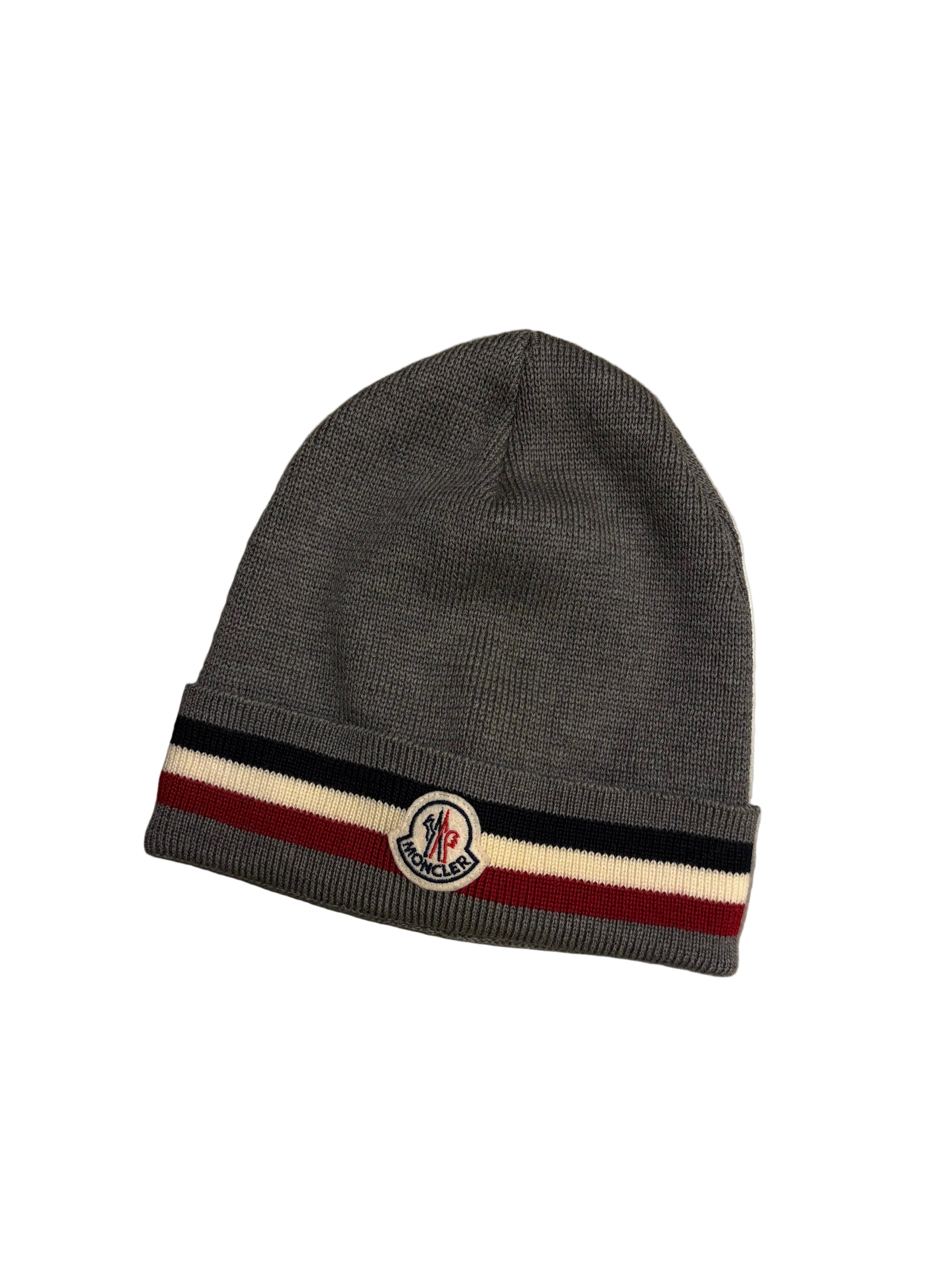 Gray beanie with a striped band and logo on a concrete surface